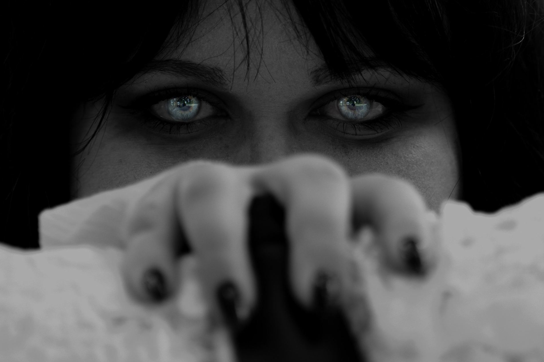 Primer plano de ojos azules detrás de una mano